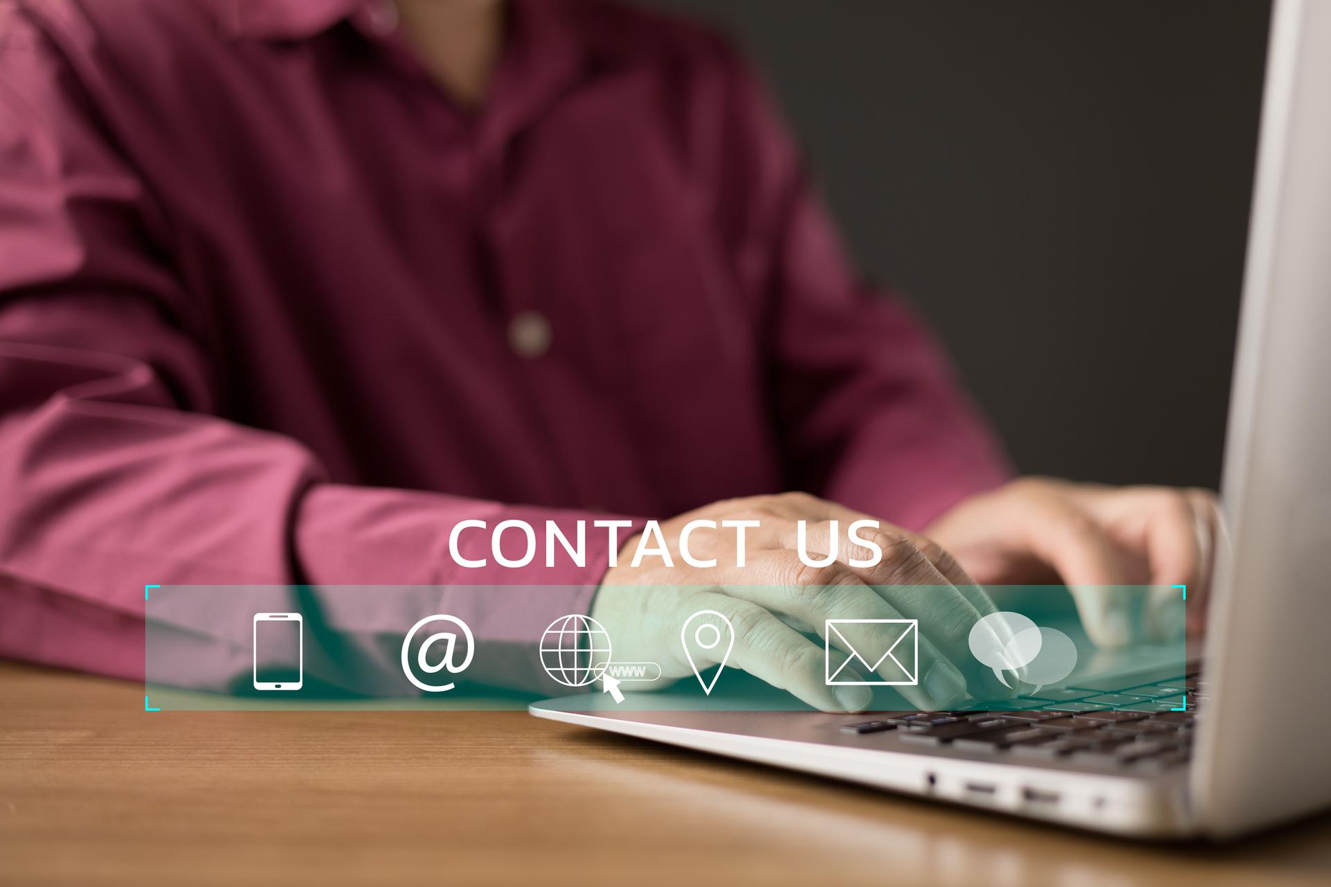 A man types on a laptop while a digital CONTACT US interface with icons for phone, email, web, location, and chat appears. The image represents connection, communication, and support.