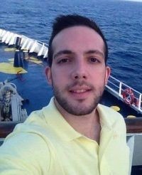 Person wearing a yellow shirt taking a selfie on a boat with the ocean in the background.